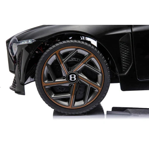 Close-up of black Bentley Bacalar electric ride on car's wheel, featuring logo on the hubcap, isolated against white background.