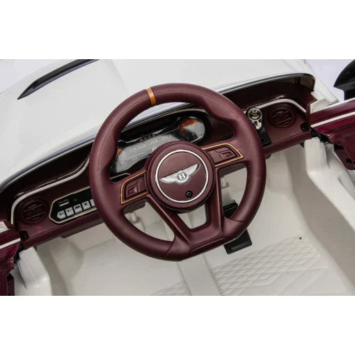 Vintage-style Bentley interior featuring maroon steering wheel and classic dashboard for children's play, along with White Bentley Bacalar Electric Ride-on Car with Parent Remote.