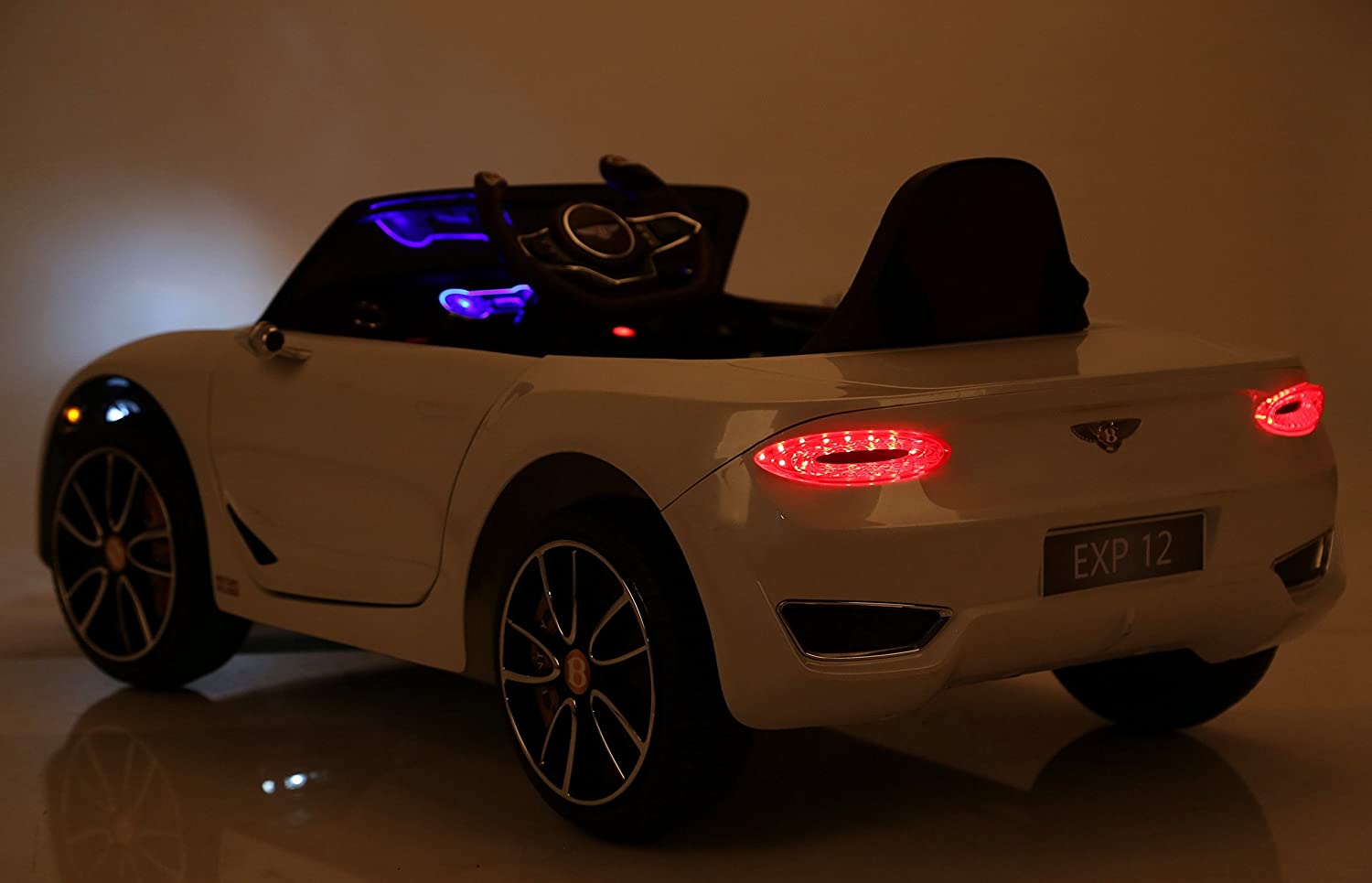 White Bentley GT EXP12 Kids Electric Ride On Car 12 Volt with illuminated interior and tail lights in a low-light setting