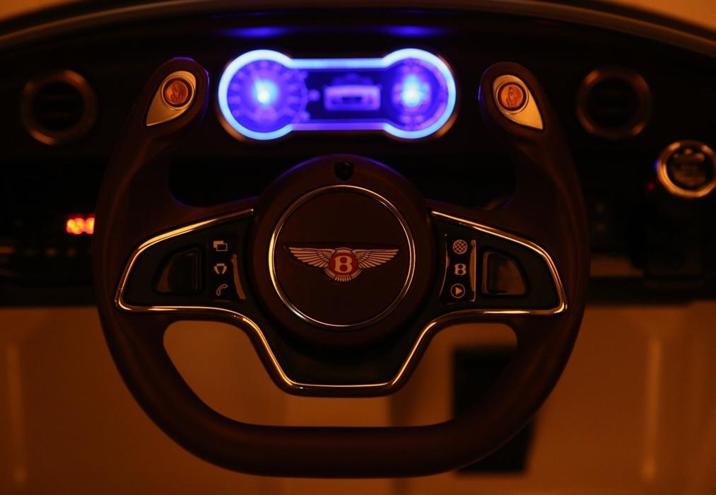 Illuminated blue lights on the steering wheel of a green Bentley GT EXP12 12 Volt electric ride-on car for kids from KidsCar.co.uk.