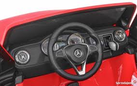 Interior shot of a red Mercedes-Benz X Class children's electric car showcasing the steering wheel and dashboard.