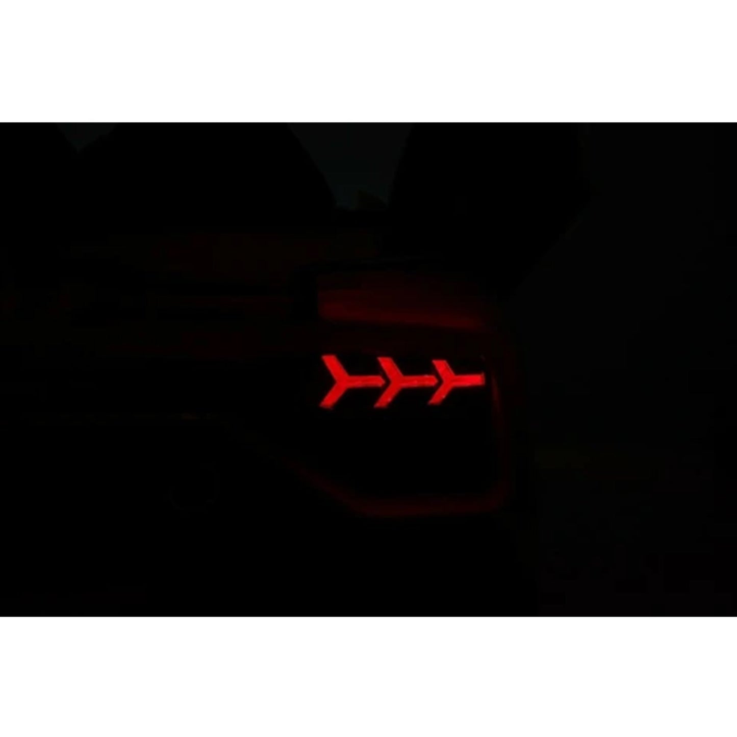 Alt text: Red illuminated taillight of Matt Black Lamborghini SVJ electric ride-on with parent remote on a dark background.