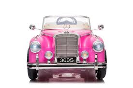 Vintage pink Mercedes-Benz 300S electric ride-on car for kids, with chrome details and license plate '300s', on a white background.